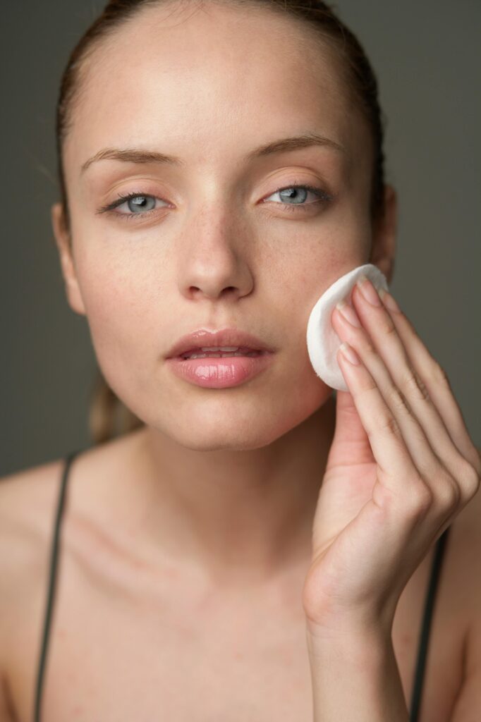 pexels-photo-12585835-12585835 Young woman using a cotton pad for skincare, highlighting beauty routine.